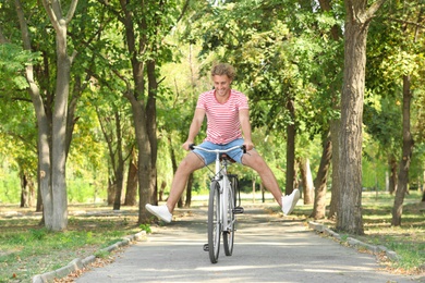 Handsome man riding bicycle in park on sunny day