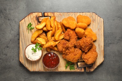 Tasty fried chicken nuggets served on grey table, top view