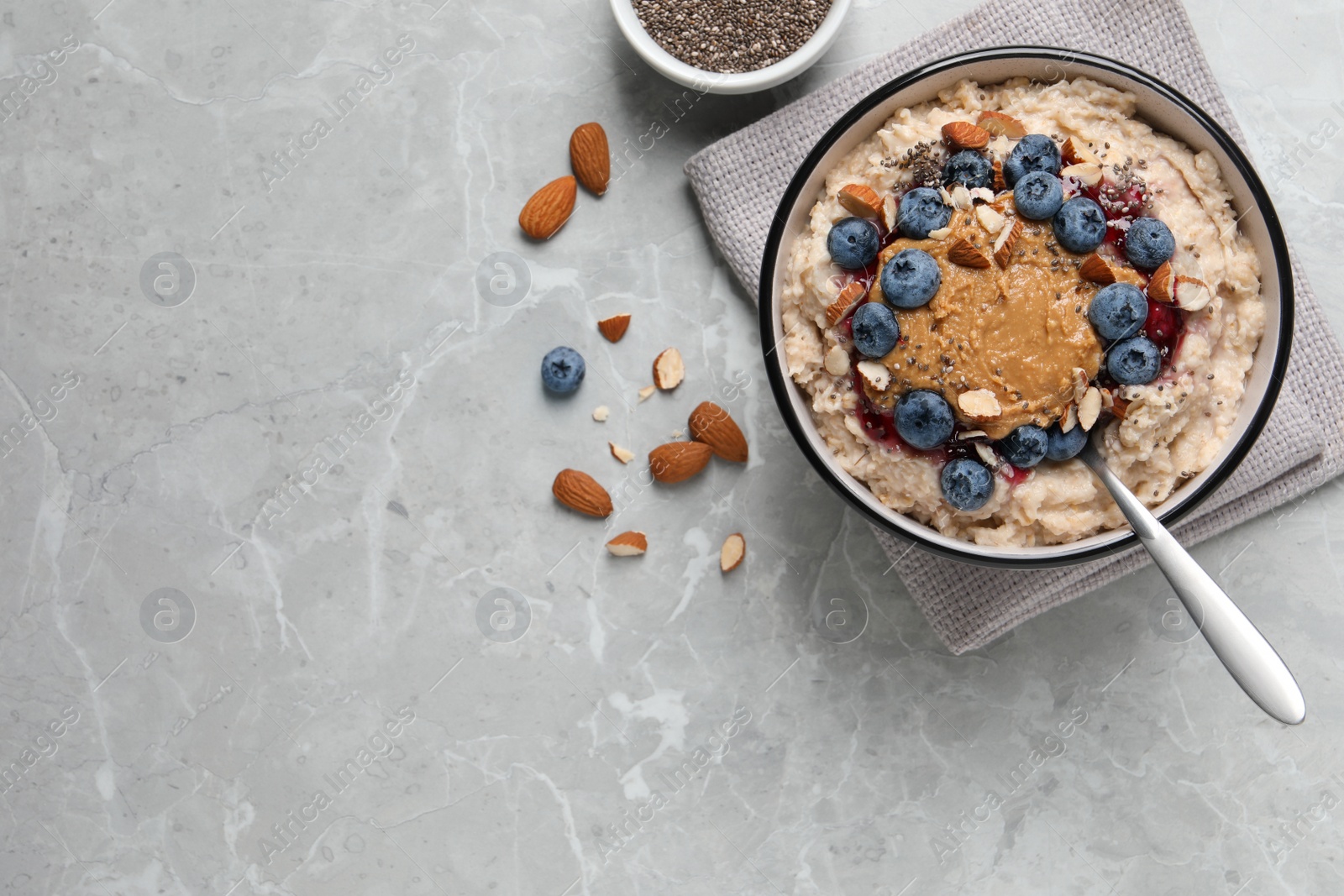 Photo of Tasty oatmeal porridge with toppings served on grey table, flat lay. Space for text