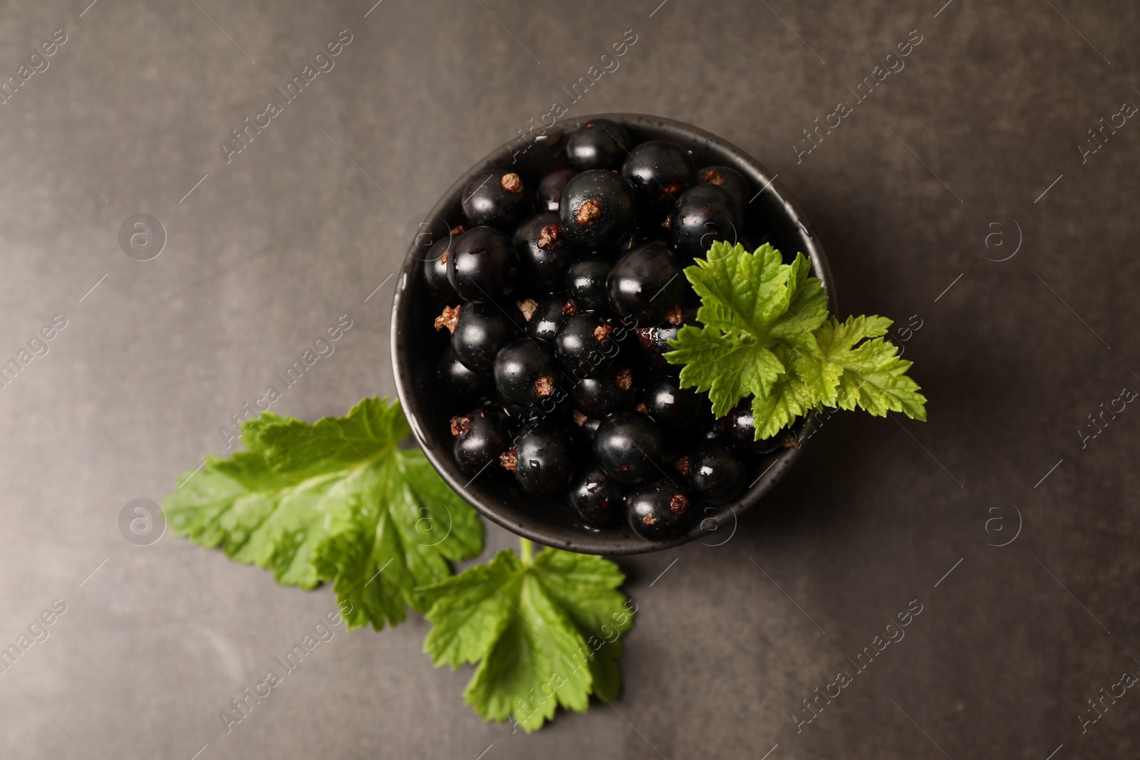 Photo of Ripe blackcurrants and leaves on grey background, flat lay