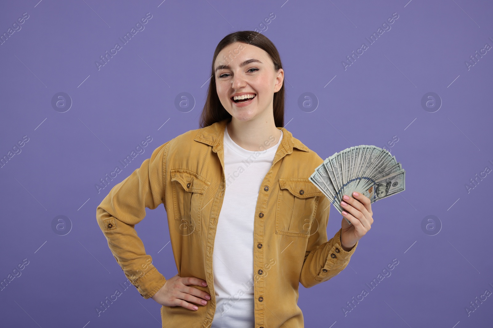 Photo of Happy woman with dollar banknotes on purple background