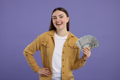 Happy woman with dollar banknotes on purple background