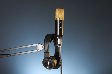 Photo of Stand with microphone and headphones on dark background. Sound recording and reinforcement