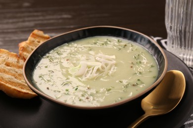 Photo of Delicious leek soup served on brown wooden table, closeup
