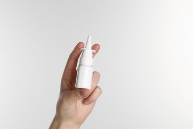 Photo of Woman holding nasal spray on white background, closeup. Space for text