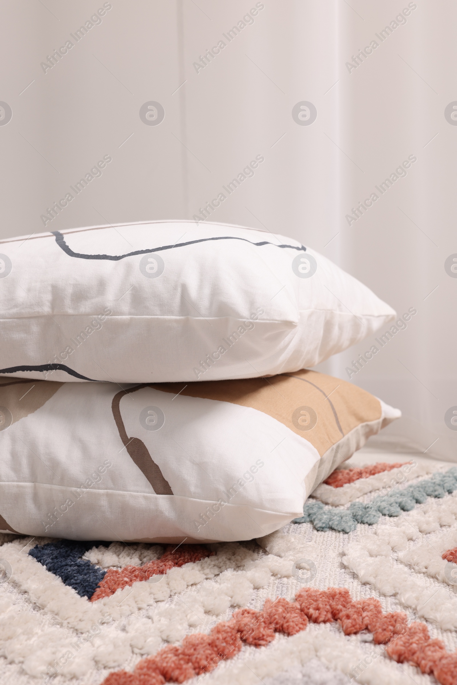 Photo of Stacked soft pillows on floor in room