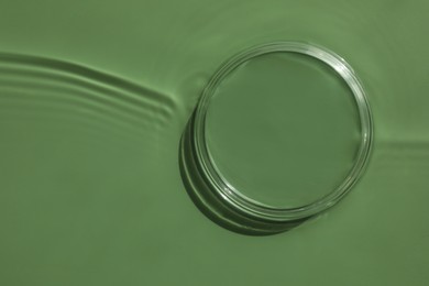 Photo of Stylish presentation for product. Glass podium in water on pale green background, top view. Space for text