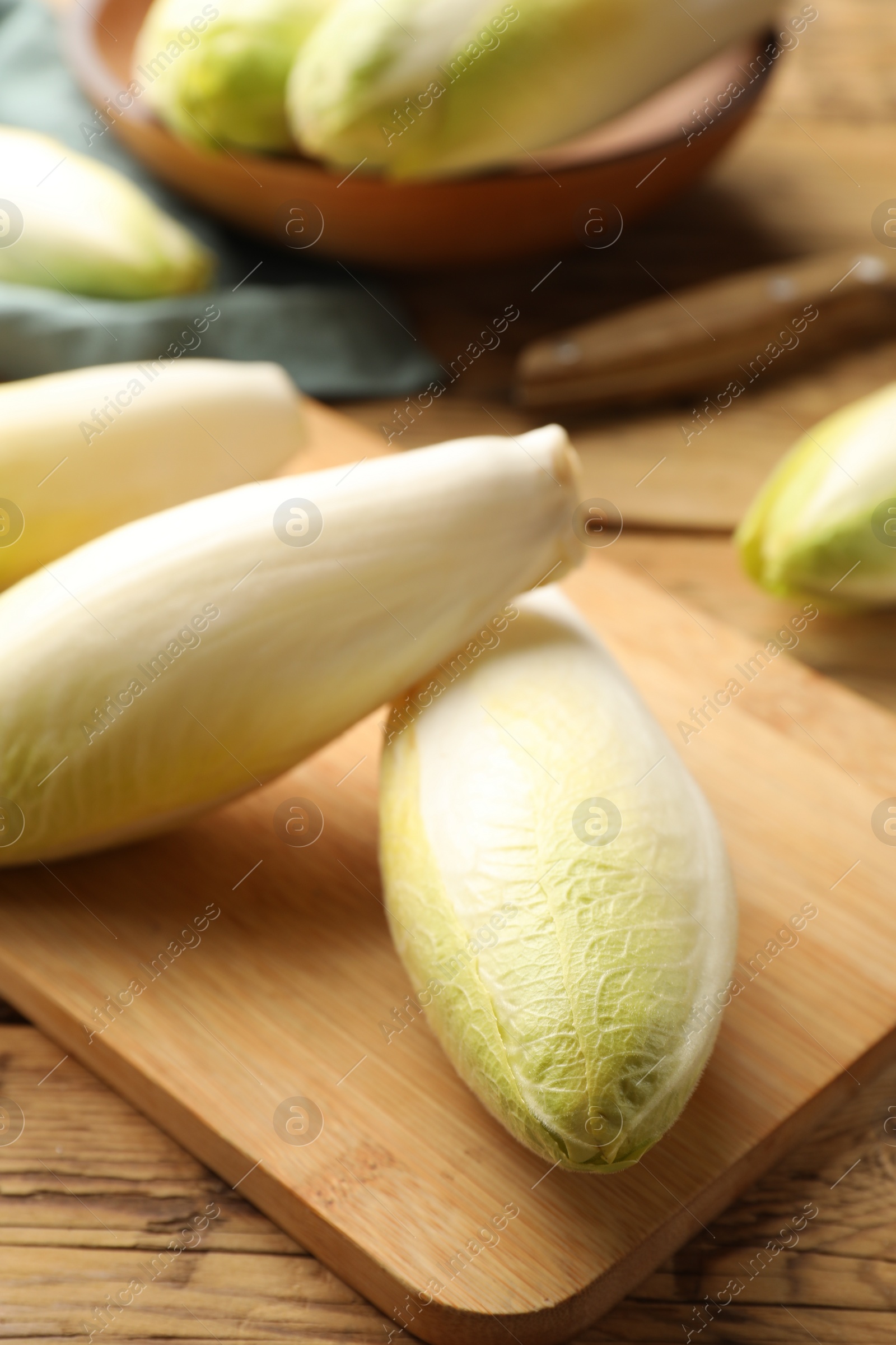 Photo of Fresh raw Belgian endives (chicory) on wooden table, closeup