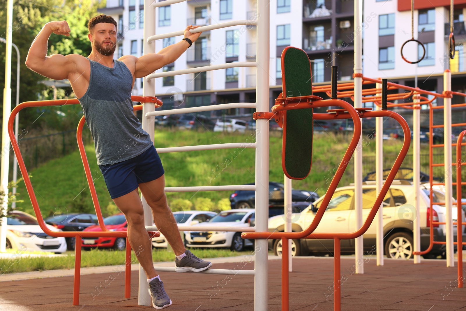 Photo of Man showing biceps at outdoor gym on sunny day