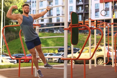 Man showing biceps at outdoor gym on sunny day