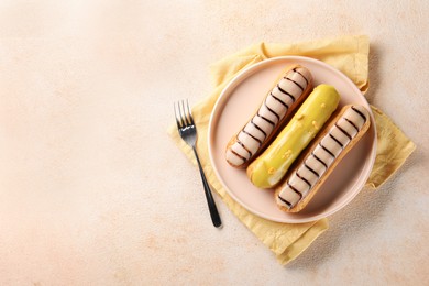 Different tasty glazed eclairs served on color textured table, top view. Space for text