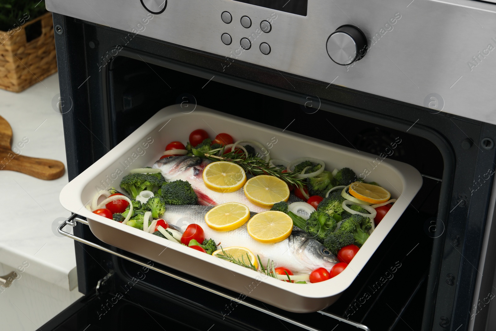 Photo of Raw fish with vegetables and lemon in baking dish into oven indoors