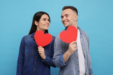 Photo of Lovely couple with decorative hearts on light blue background. Valentine's day celebration