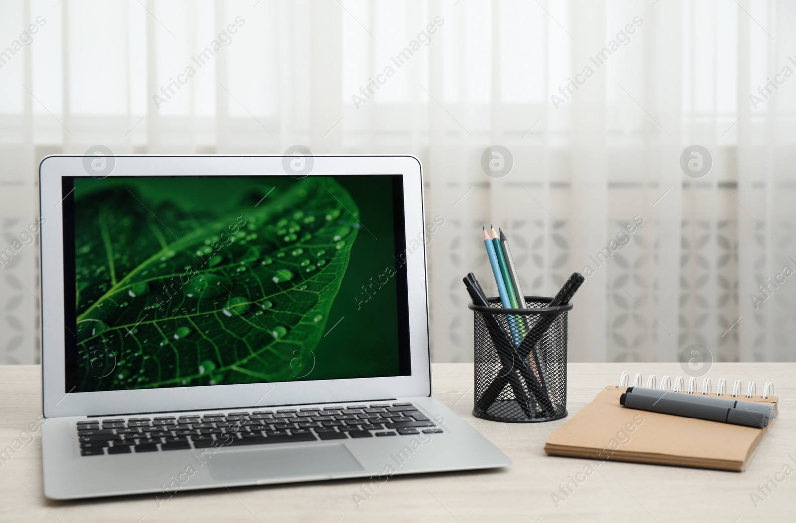 Photo of Modern laptop and supplies on wooden table indoors