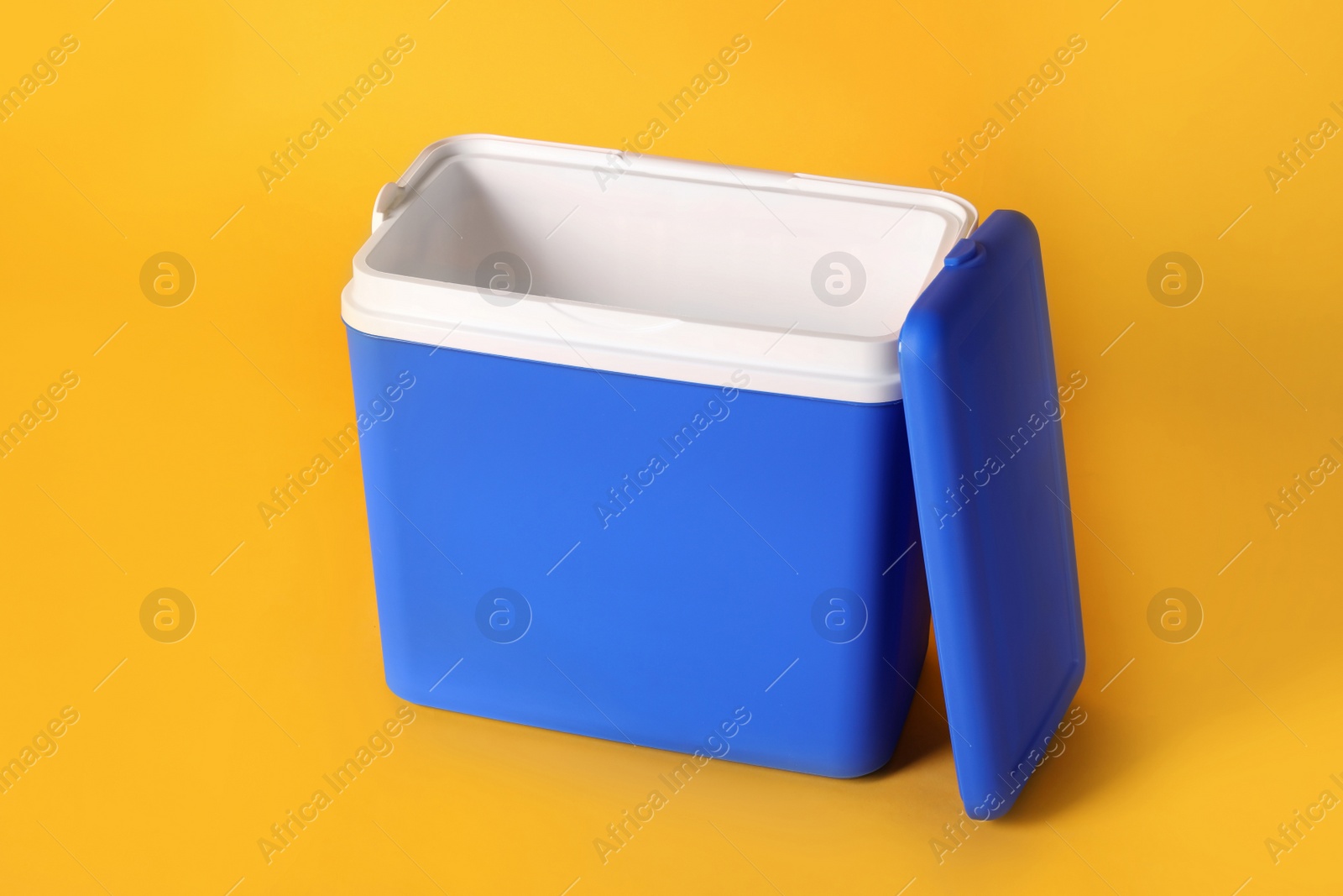 Photo of Open blue plastic cool box on orange background