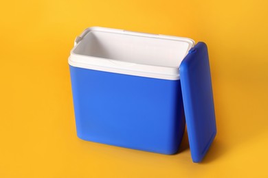 Photo of Open blue plastic cool box on orange background