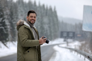 Photo of Male photographer with camera on snowy road, space for text. Winter vacation