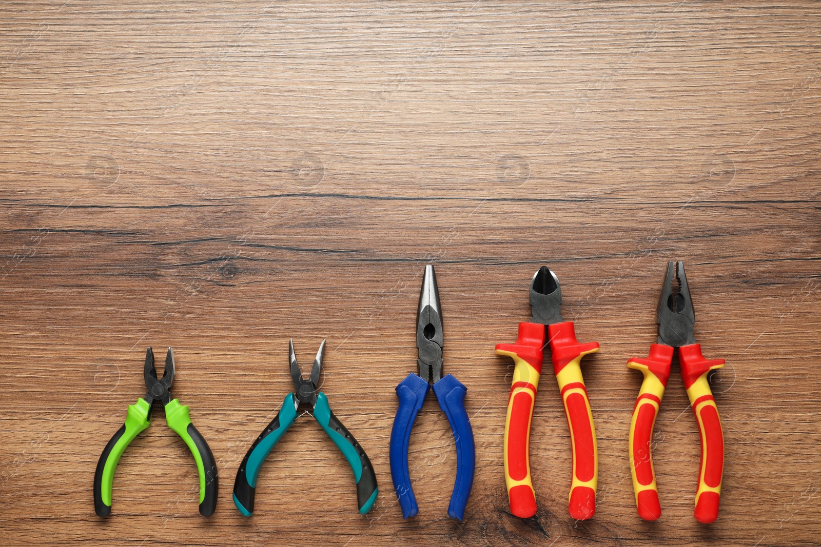 Photo of Different pliers on wooden table, flat lay. Space for text