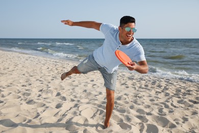 Happy man throwing flying disk at beach on sunny day