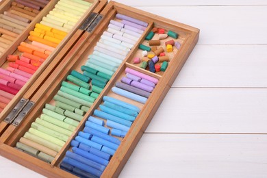 Photo of Set of soft pastels in box on white wooden table, space for text. Drawing material