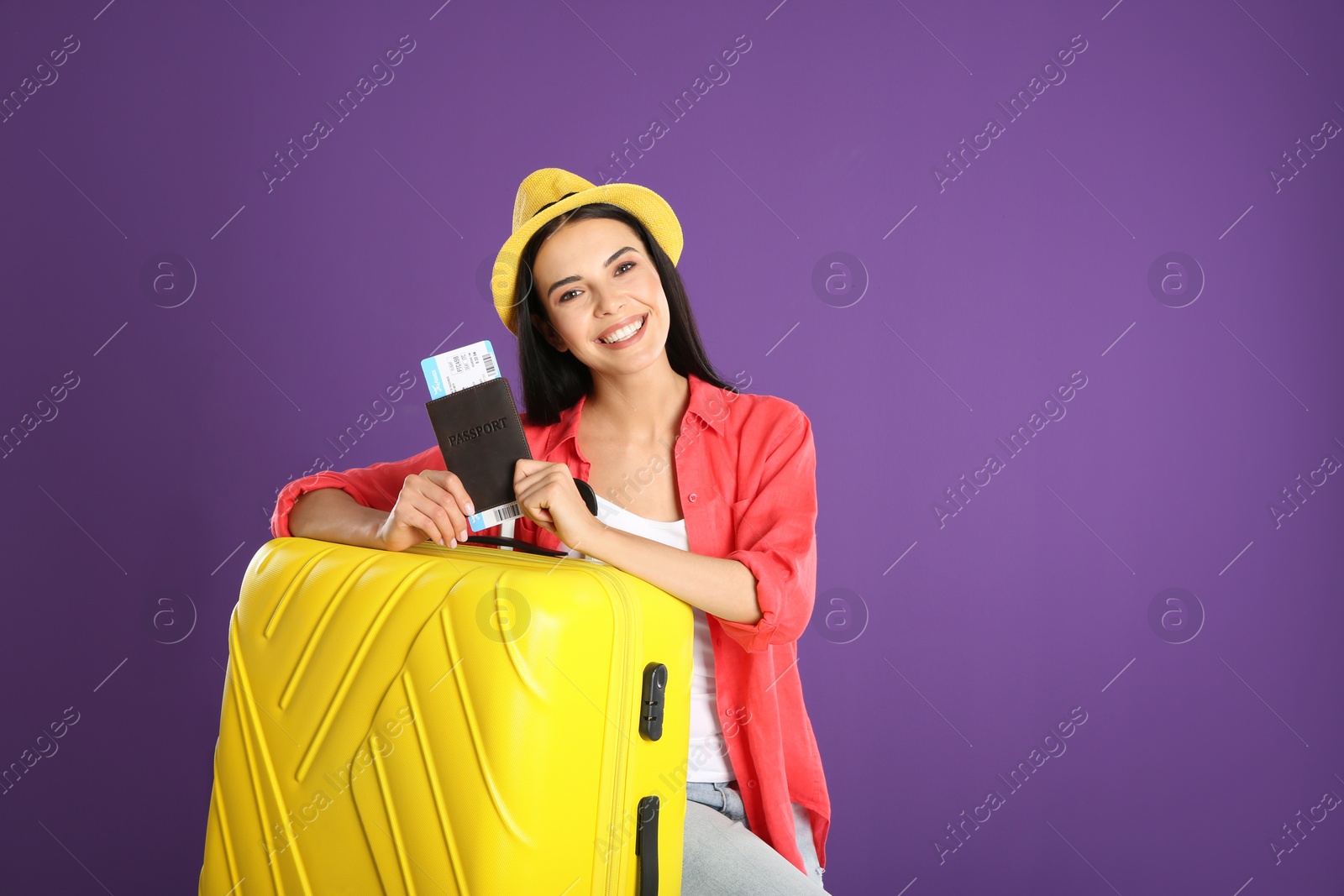 Photo of Beautiful woman with suitcase and ticket in passport for summer trip on purple background. Vacation travel