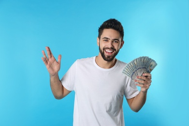 Portrait of happy young man with money on color background