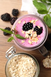 Delicious blackberry smoothie, oatmeal and berries on wooden table, flat lay