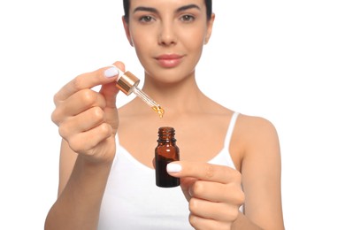Photo of Young woman with bottle of essential oil against white background, focus on hands