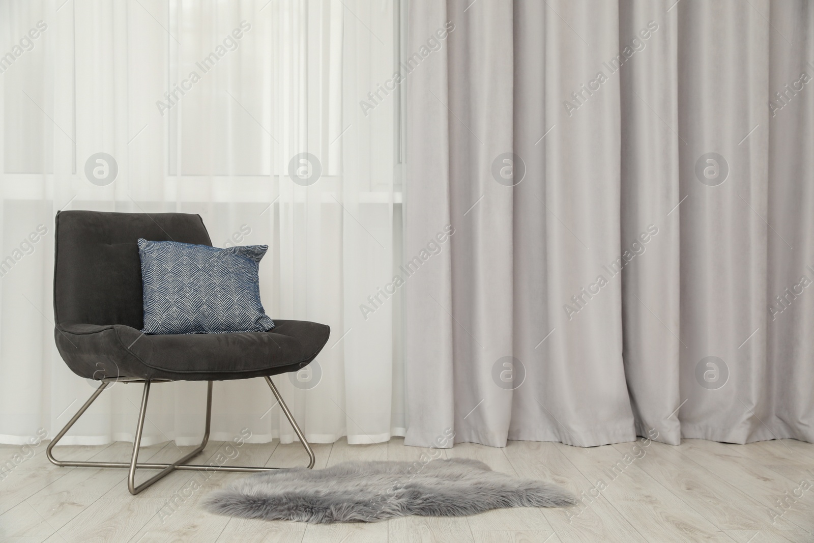 Photo of Light gray window curtain and armchair indoors