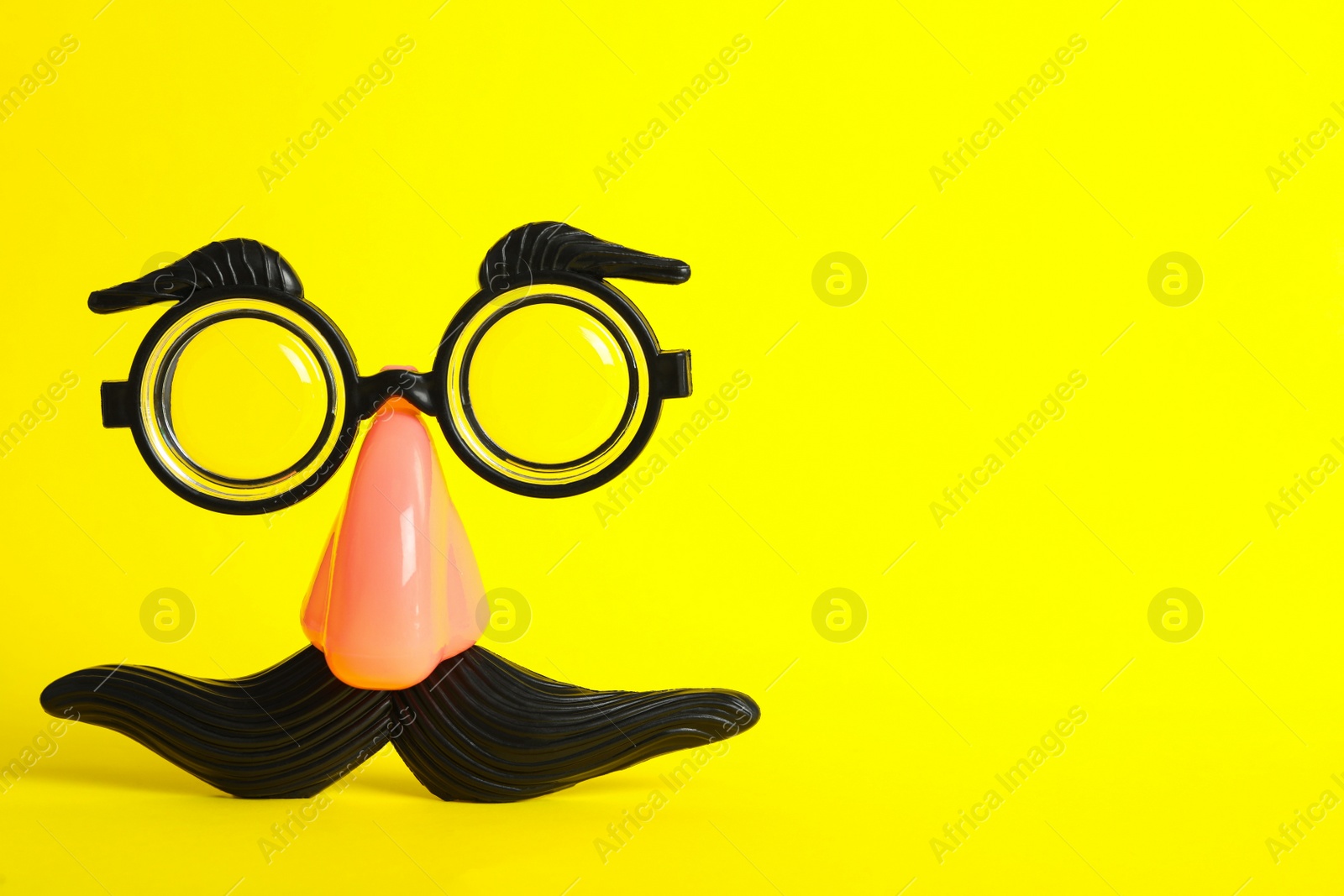 Photo of Funny face made with clown's accessories on yellow background, space for text