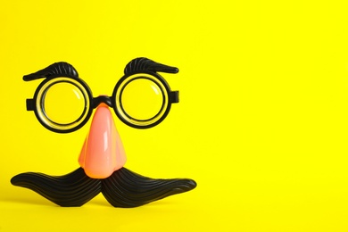 Photo of Funny face made with clown's accessories on yellow background, space for text