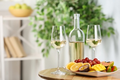 Delicious exotic fruits and wine on wooden table indoors, space for text