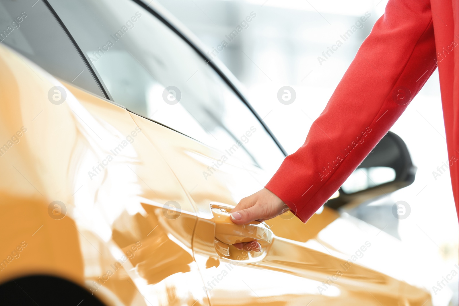 Photo of Young woman opening door of new car, closeup