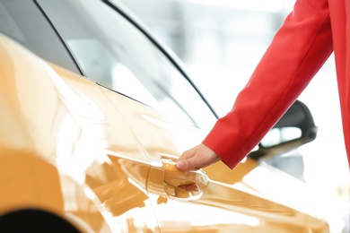 Photo of Young woman opening door of new car, closeup