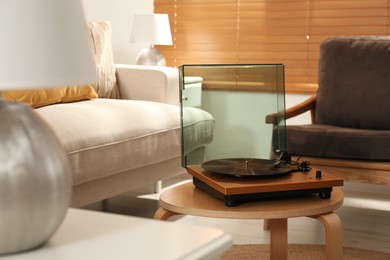 Modern vinyl record player with disc on table indoors