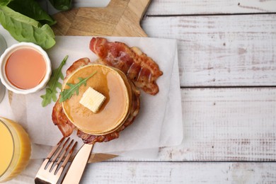 Delicious pancakes with bacon served on light wooden table, flat lay. Space for text