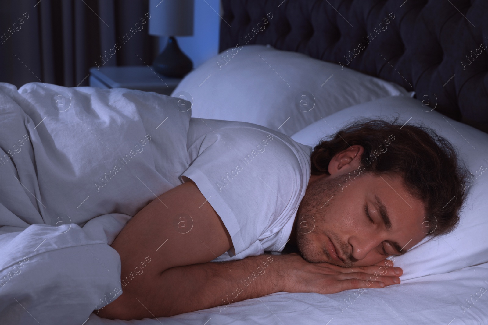 Photo of Handsome young man sleeping on pillow at night. Bedtime