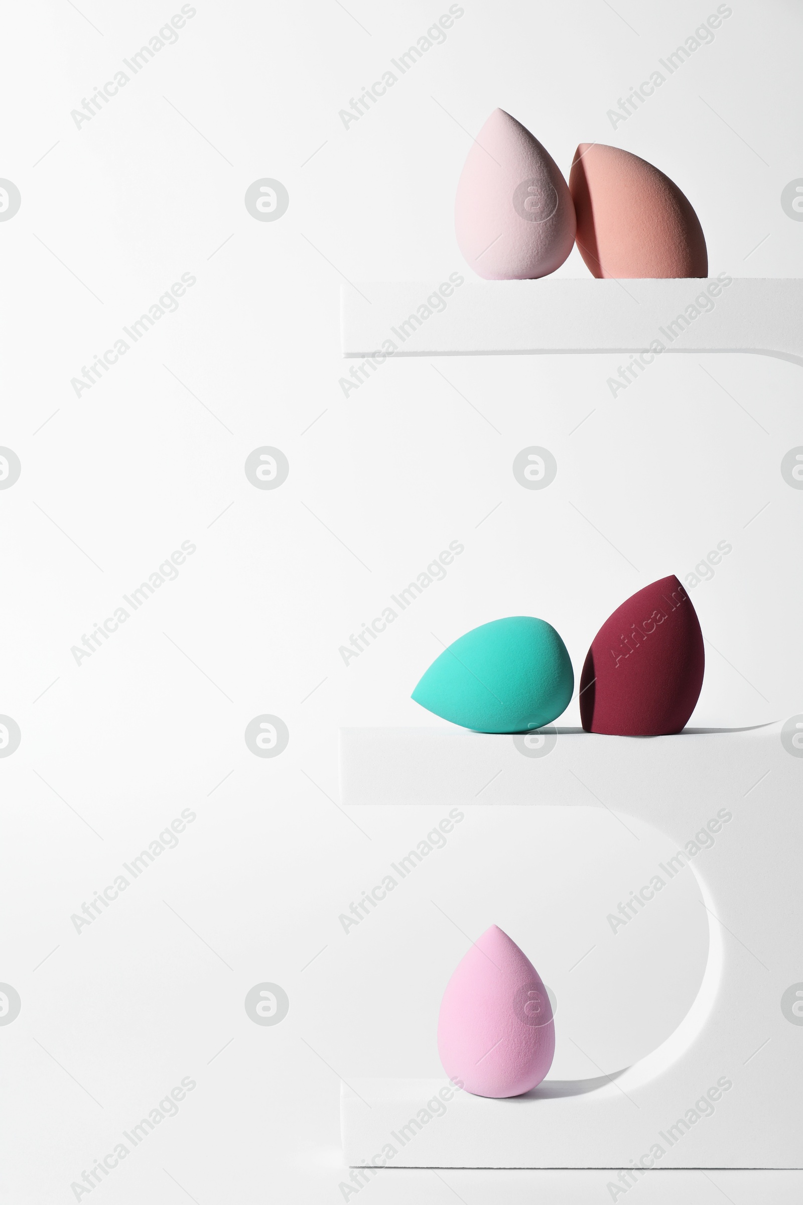 Photo of Stylish presentation of makeup sponges on white background