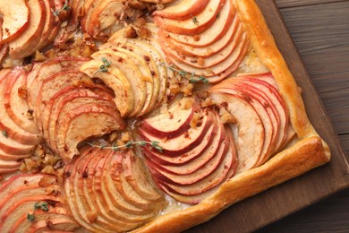 Photo of Freshly baked apple pie with nuts on wooden table, top view