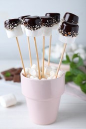 Delicious marshmallows covered with chocolate on white wooden table