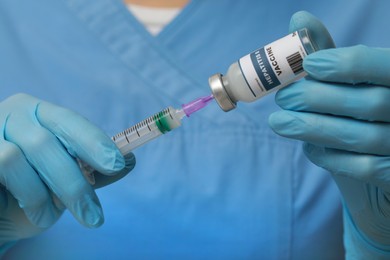 Doctor filling syringe with hepatitis vaccine from glass vial, closeup