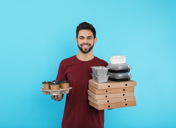 Young courier with different orders on color background. Food delivery service