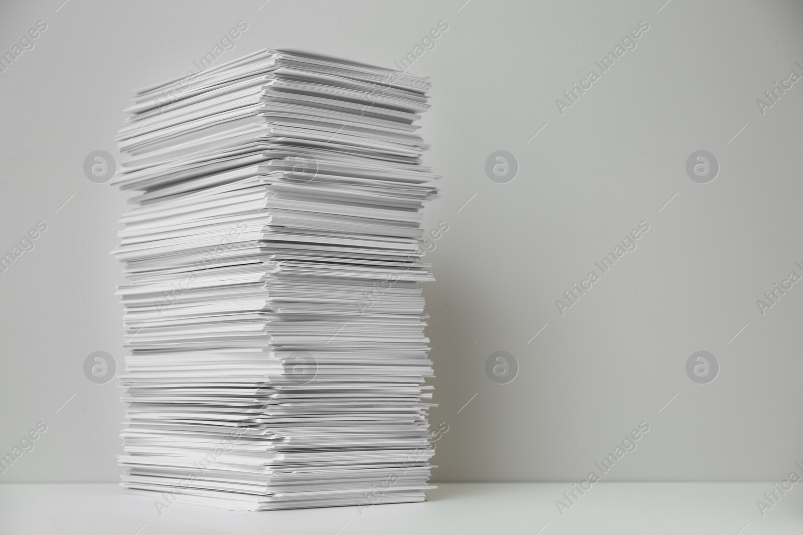 Photo of Stack of paper sheets on white table. Space for text