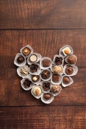 Heart made with delicious chocolate candies on wooden table, top view