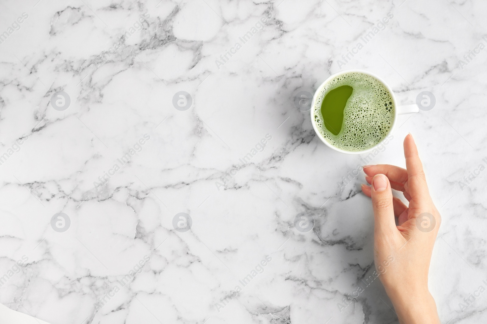 Photo of Woman with cup of matcha tea at table, top view