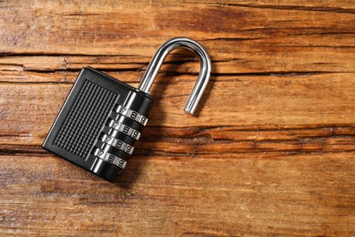 One steel combination padlock on wooden table, top view. Space for text