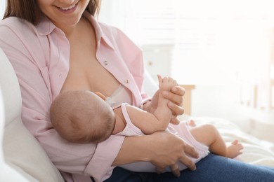 Young woman breastfeeding her little baby at home, closeup