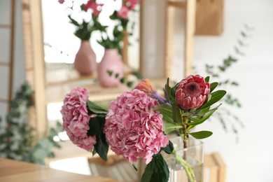 Photo of Vase with fresh beautiful flowers in florist's workshop