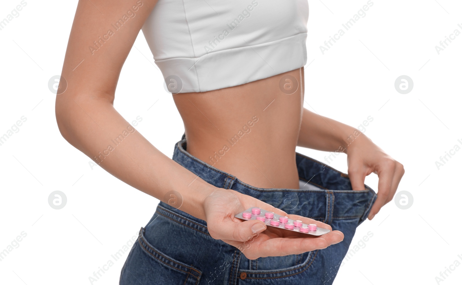 Photo of Slim woman in big jeans with pills on white background, closeup. Weight loss