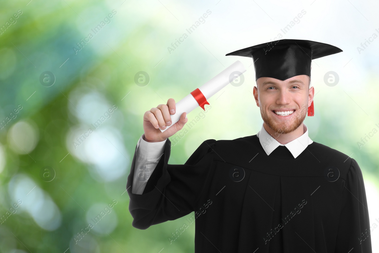 Image of Happy student with graduation hat and diploma on blurred background, space for text